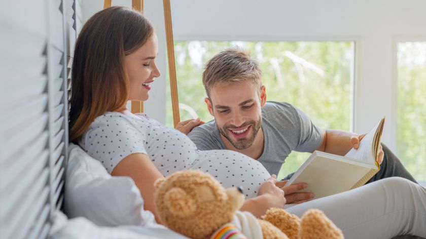 Schwangere Frau mit Partner auf dem Bett