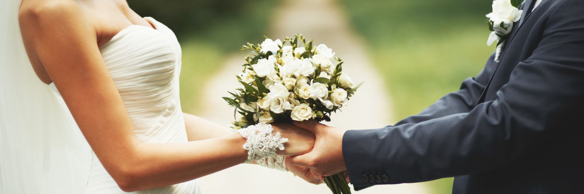 Brautpaar hält seine Hände mit Brautstrauss